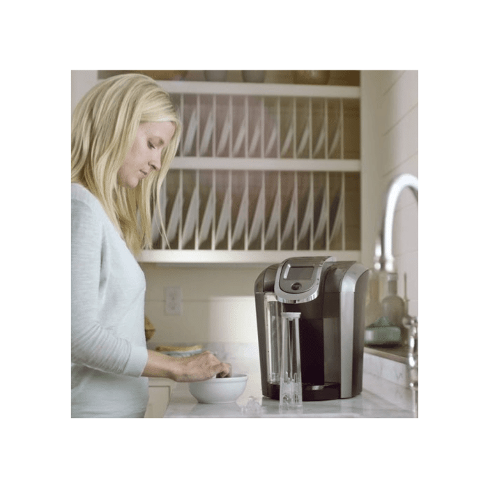 woman using keurig water filter starter kit in kitchen